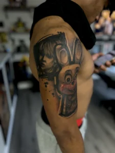 black and gray cross and cartoon arm tattoo jeff thibodaux tattootopia