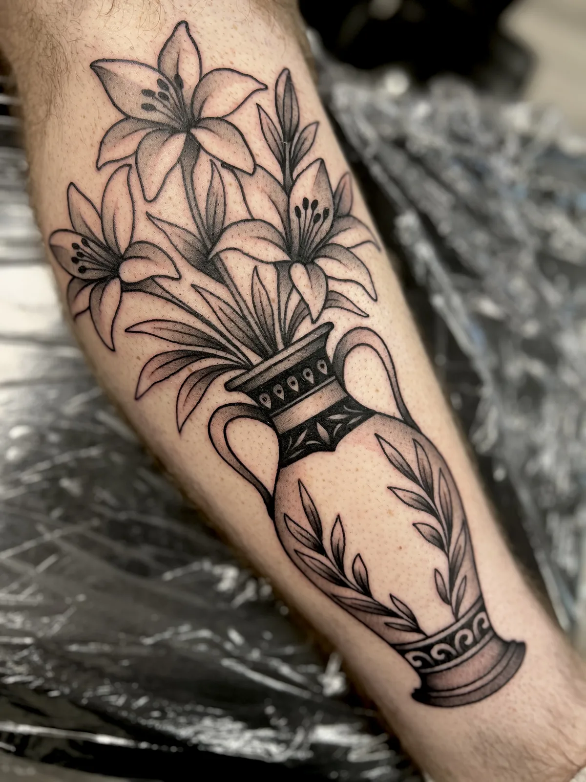 black and gray lilies in an urn leg tattoo jeff thibodaux tattootopia