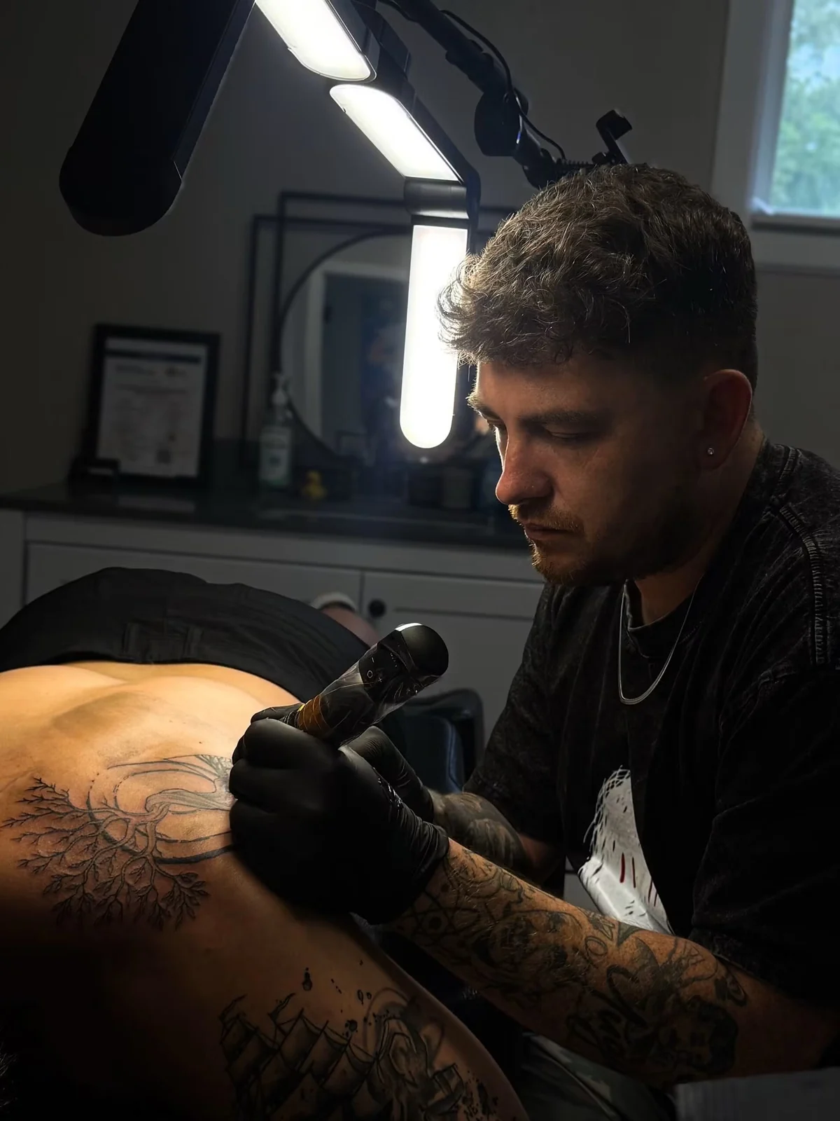 Jeff Thibodaux tattooing a client at Tattootopia in Denham Springs
